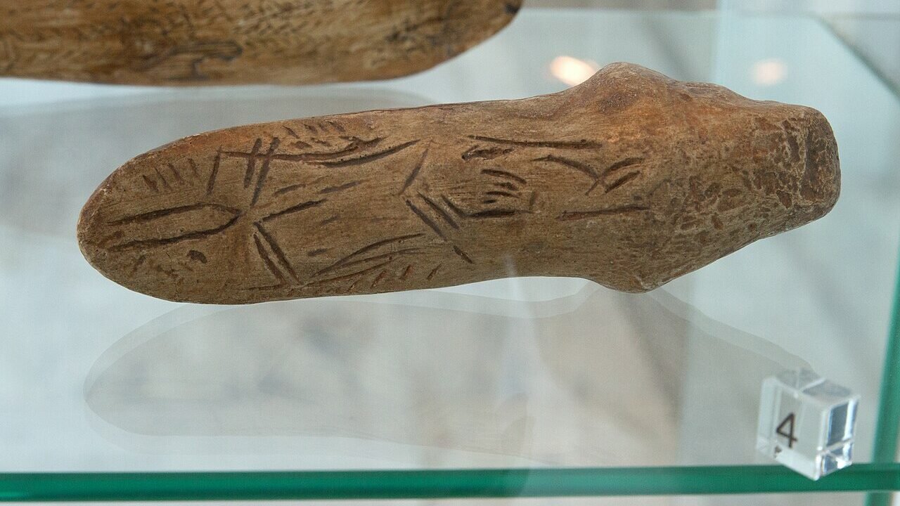 Sculptură paleolitică puternic stilizată, reprezentând probabil o femeie, expusă într-o vitrină de muzeu