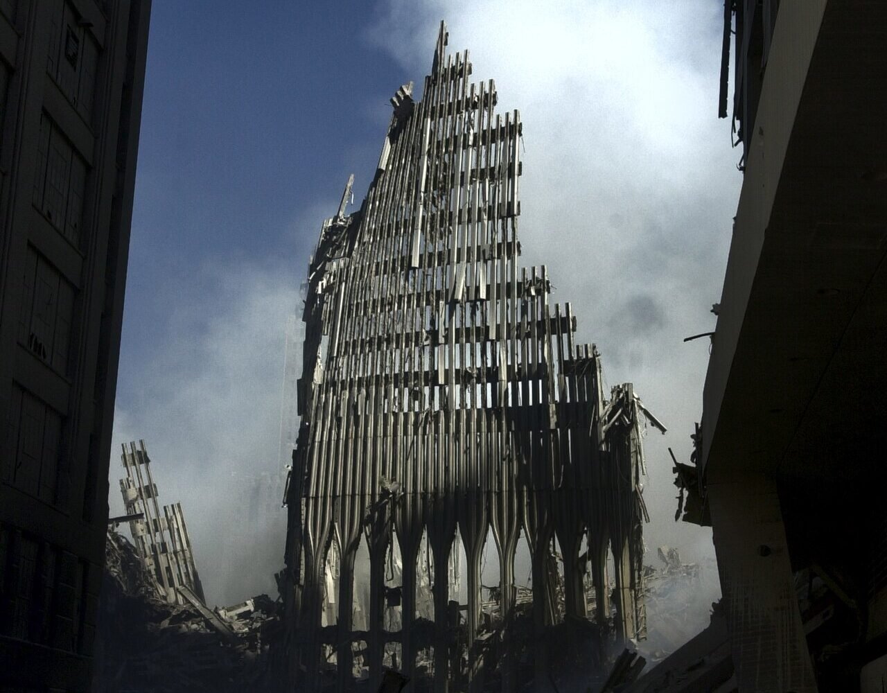 Structura metalică rămasă din turnul sudic al World Trade Center, printre fum și dărâmături, la New York