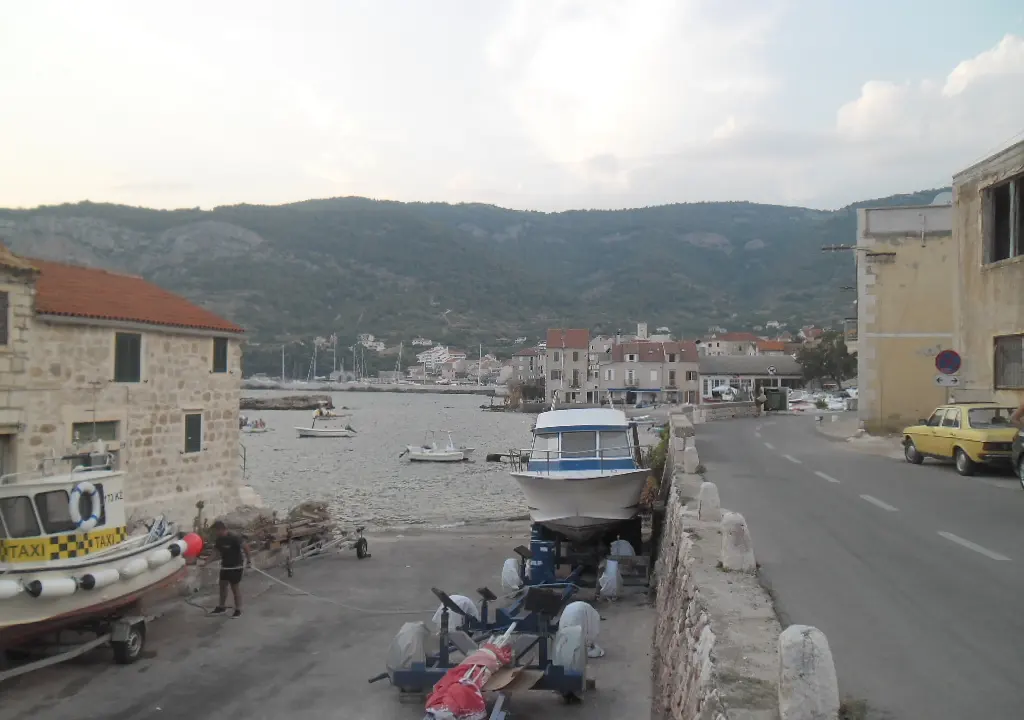 Orașul Komiža văzut de pe mare, cu case albe la poalele dealurilor